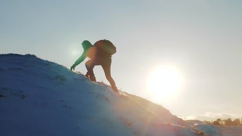 success victory win business travel concept. rock climber rises to the top of a snowy mountain sunset silhouette snow. overcoming the difficulties of the problem, the tourist rises to the top of the