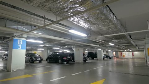 Voronezh, Russia - Circa September 2018 : Underground automobile parking lot with columns and many cars in modern mall or shopping center.