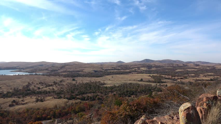 View of beautiful landscape with lake and autumn colors of wild growing trees and brush. View from Wichita Mountains.
