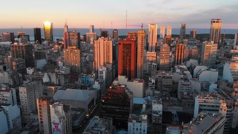 Panoramic aerial drone view of Buenos Aires city downtown in late afternoon over skyscraper buildings, cars and traffic visible in the streets below. Puerto Madero and San Telmo in the background.