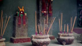 This video shows a artistic and tranquil view of large pots of incense burning at a beautiful temple.
