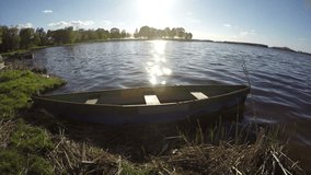 old wooden fishing boat on lake water in spring evening.Timelapse 4K 

