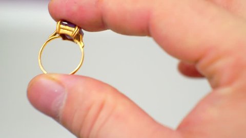 men's hands hold a small female gold engagement ring with a precious stone.
closeup