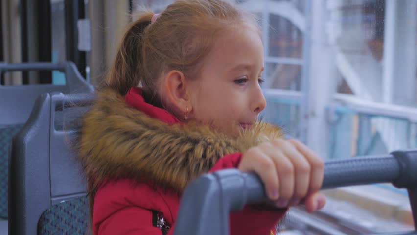 Little girl is looking through window while sitting in train.