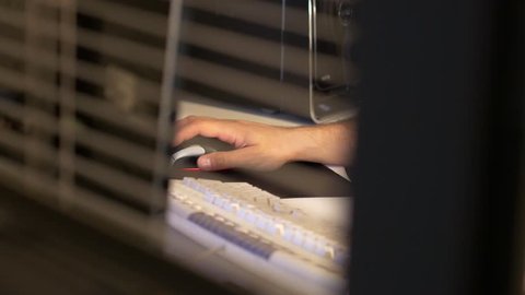 Peaking in through window at a person using a computer keyboard and mouse