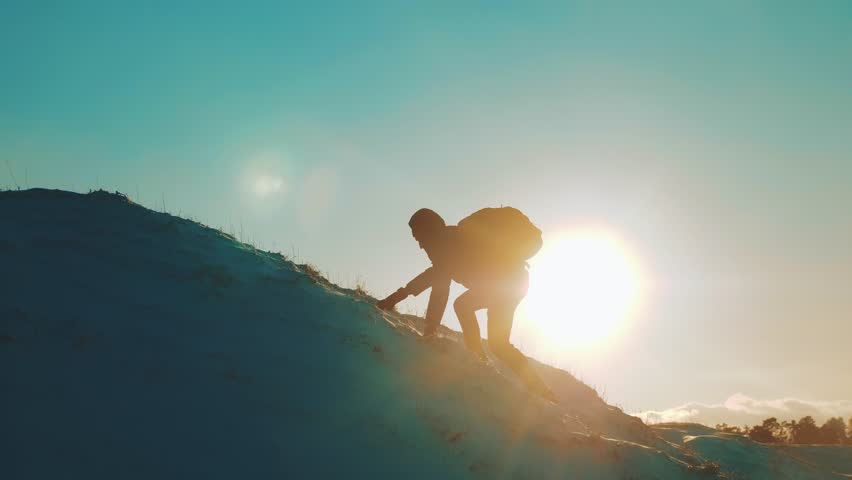 Success victory win business travel concept. rock climber rises to the top of a snowy mountain sunset silhouette snow. overcoming the difficulties of the problem, the tourist rises to the top of the | Shutterstock HD Video #1020392095