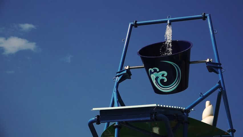 Amusement park poured water from the bucket on the hill. Slow motion. Close up