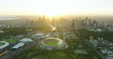 Melbourne - March 2018: Aerial view with sun flare Melbourne Cricket Ground Yarra Park with city skyscrapers at sunset Victoria Australia