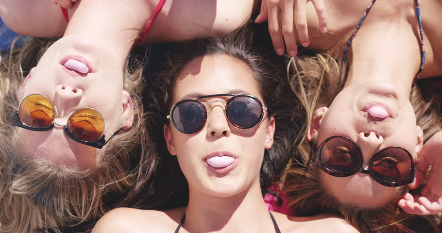 Top view of three teenage girl friends lying on back blowing bubblegum candy bubbles on beach Royalty-Free Stock Footage #10204007