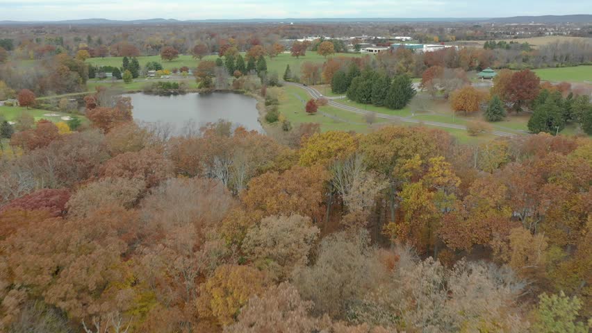 Autumn aerial view follows a quiet Mohonk Mountain pond bordered by colorful woodland and reflective water near New Paltz, 2018.