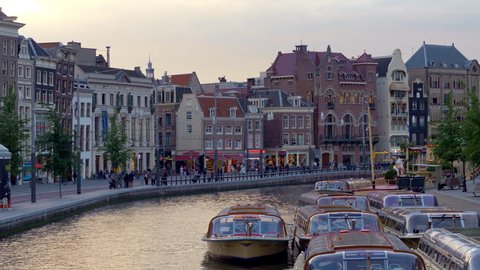 AMSTERDAM, NETHERLANDS - JUNE, 2018: Amazing cityscape of Amsterdam with famous canals and embankments at sunset time.