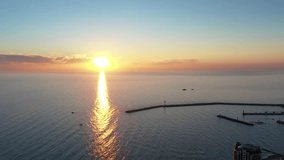 Aerial view: Sunset over the sea in the background boats,sailing boat, orange sky. Sailing boat at sunset in the sea. Travel concept. Beautiful serene scene. Beautiful sunset over sea, aerial video