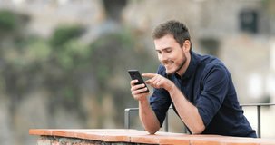 Happy man browsing smart phone content in a rural apartment balcony