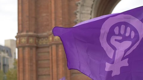 Feminist Flag waving in front of Arc de Triomf in Barcelona. Feminist Activists in a Demonstration. March for the International Day of Nonviolence against Women and Children in Barcelona, Spain.