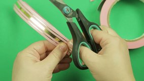 Female hands wrapping a pink ribbon pattern on a green background