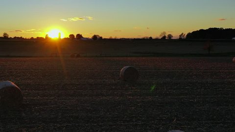 Cool shot past bales of hay on a pasture during a picturesque sunset