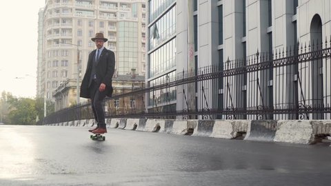 Hipster businessman wear a hat and glasses skateboarding near business office
