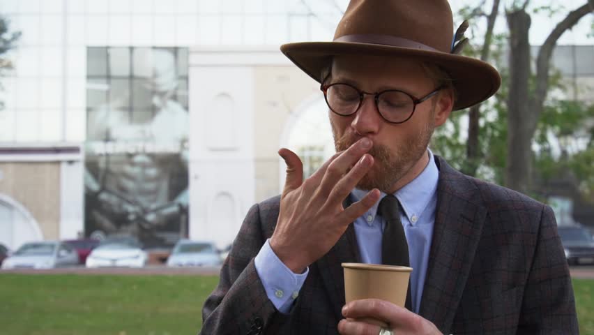 Portrait of handsome hipster guy eating cappuccino foam licking his finger