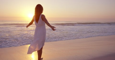 Free happy woman spinning arms outstretched enjoying natural lifestyle dancing on beach at sunset slow motion RED DRAGON
