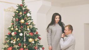 young couple in love in new year decor with gifts and christmas tree, there is noise in the video
