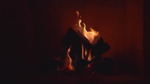 Fireplace burning in darkness. Wide shot in slow motion.