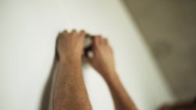 Male's hands are professionally and actively driving heavy staples into white wallpapers by using staple-gun somewhere in workhouse room. - Powered by Shutterstock - Get 15% off with code: PIKWIZARD15