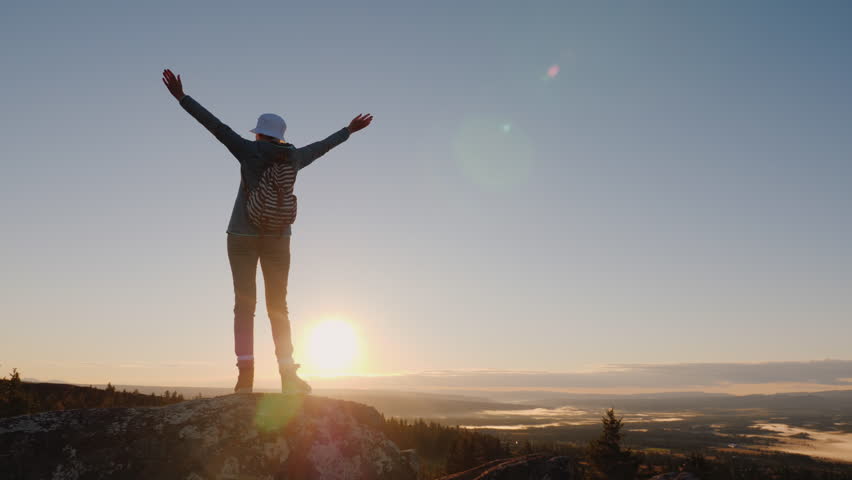 Crane shot of A successful woman traveler at the top of the mountain raises her hands up. Reach the top of the concept. | Shutterstock HD Video #1020450157