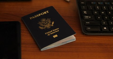 Camera pushes in on Passport as a female hand grab the passport from the table