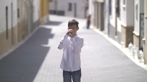 spanish boy drinking a drink outdoors standing near camera