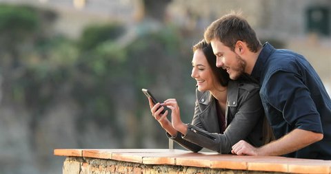 Surprised couple checking smart phone content in a rural apartment terrace