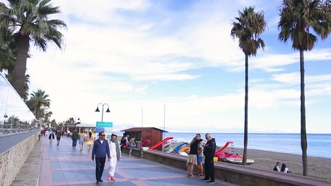 Torremolinos , Malaga , Spain - November 24, 2018 : Sea front view and promenade , people walking and enjoying a sunny day of November in south of Spain, the famous Carihuela Beach Area