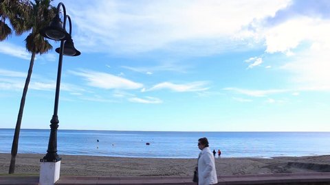 Torremolinos , Malaga , Spain - November 24, 2018 : Sea front view and promenade , people walking and enjoying a sunny day of November in south of Spain, the famous Carihuela Beach Area
