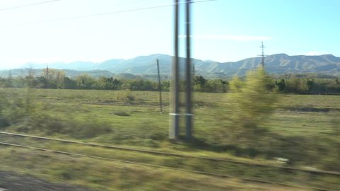 View from the high speed train at beautiful Georgian landscapes with hills and forest. Window view from car, bus, train. Traveling from train on a sunny day. Train from Tbilisi to Batumi, Georgia