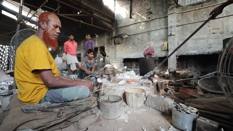 DHAKA, BANGLADESH - DECEMBER 01, 2018: Aluminium factory sweatshop with children and adultsworking in dangerous and unsafe circumstances making aluminium teapots