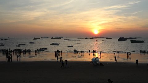 CHITTAGONG, BANGLADESH - DECEMBER 04, 2018: Sunset and sundowners with people enjoying and the sun sinking in the sea and many boats in the water at the Patenga Beach in Bangladesh