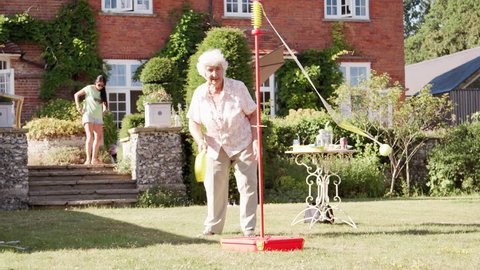 Active Senior Woman Playing Game With Bat And Ball In Garden