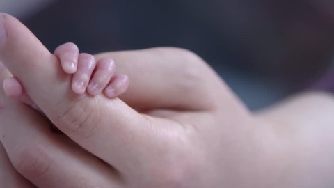 a newborn baby and his mother's hand
