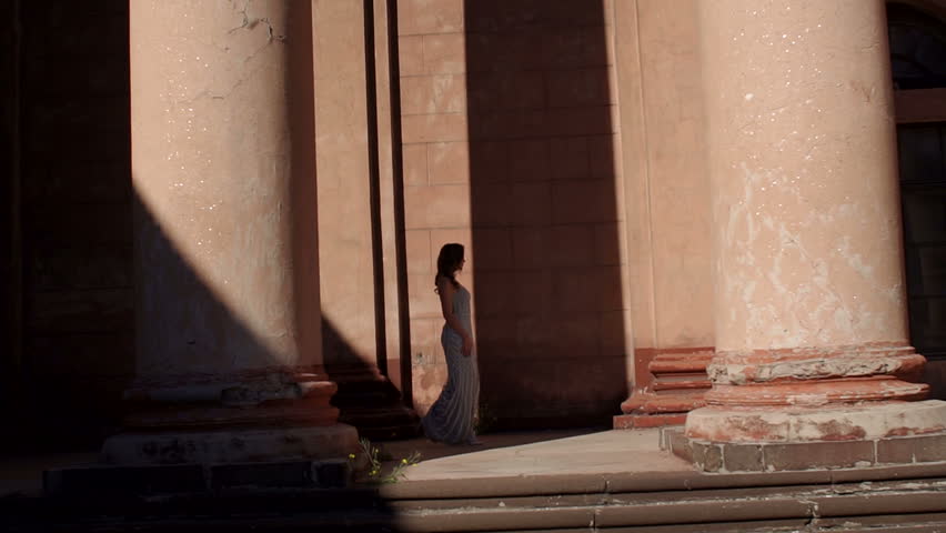An elegant lady in a long shiny evening dress walks near an ancient building with long antique columns. Portrait of a luxurious elegant girl in the fall in an old park. | Shutterstock HD Video #1020504751