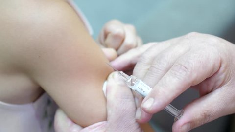 Doctor makes vaccination in the children's hands. Injection of a syringe in the shoulder close-up. 4k