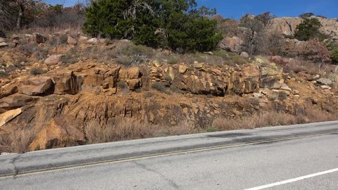 View of mountain road going up to the top of Wichita Mountains with rocks, autumn colors of wild plants beside the road.