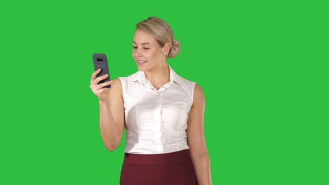 Young woman looking at smartphone thinking and reading on a Green Screen, Chroma Key.
