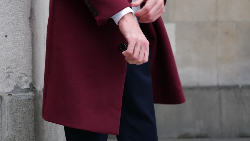 Man in red fashion coat walking. Focus on hands.