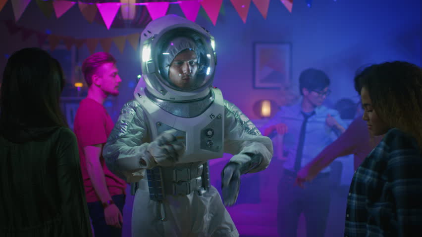 At the College House Costume Party: Fun Guy Wearing Space Suit Dances Off, Doing Groovy Funky Robot Dance Modern Moves. With Him Beautiful Girls and Boys Dancing in Neon Lights. In Slow Motion. Royalty-Free Stock Footage #1020543019