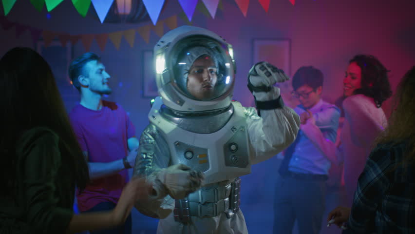 At the College House Costume Party: Fun Guy Wearing Space Suit Dances Off, Doing Groovy Funky Robot Dance Modern Moves. With Him Beautiful Girls and Boys Dancing in Neon Lights. In Slow Motion. Royalty-Free Stock Footage #1020543019