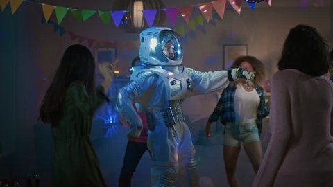 At the College House Costume Party: Fun Guy Wearing Space Suit Dances Off, Doing Robot Dance Modern Moves. With Him Beautiful Girls and Boys Dancing in Neon Lights.