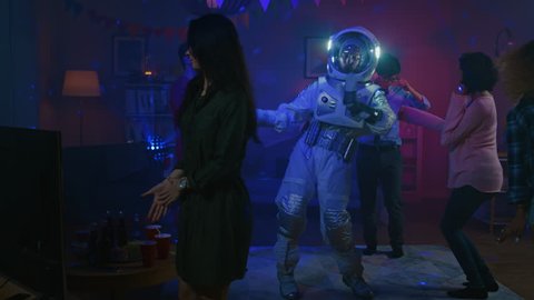 At the College House Costume Party: Fun Guy Wearing Space Suit Dances Off, Doing Groovy Funky Robot Dance Modern Moves. With Him Beautiful Girls and Boys Dancing in Neon Lights.
