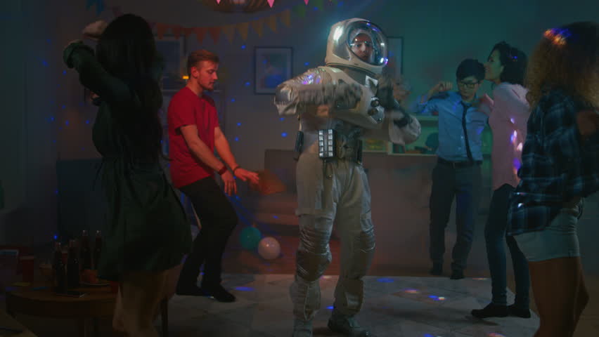 At the College House Costume Party: Fun Guy Wearing Space Suit Dances Off, Doing Groovy Funky Robot Dance Modern Moves. With Him Beautiful Girls and Boys Dancing in Neon Lights. In Slow Motion. Royalty-Free Stock Footage #1020544123