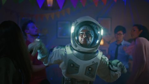At the College House Costume Party: Fun Guy Wearing Space Suit Dances Off, Doing Groovy Funky Robot Dance Modern Moves. With Him Beautiful Girls and Boys Dancing in Neon Lights.
