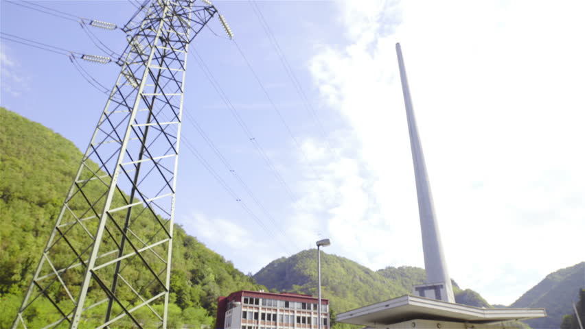 Man make a call checking about big chimney HD. Male worker stand under electric tower and with Thermal power plant chimney in background on a sunny day.