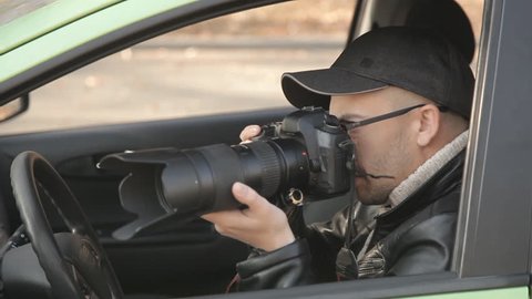 A private detective or a spy conducts surveillance of the object of surveillance. A man secretly taking pictures from the car window